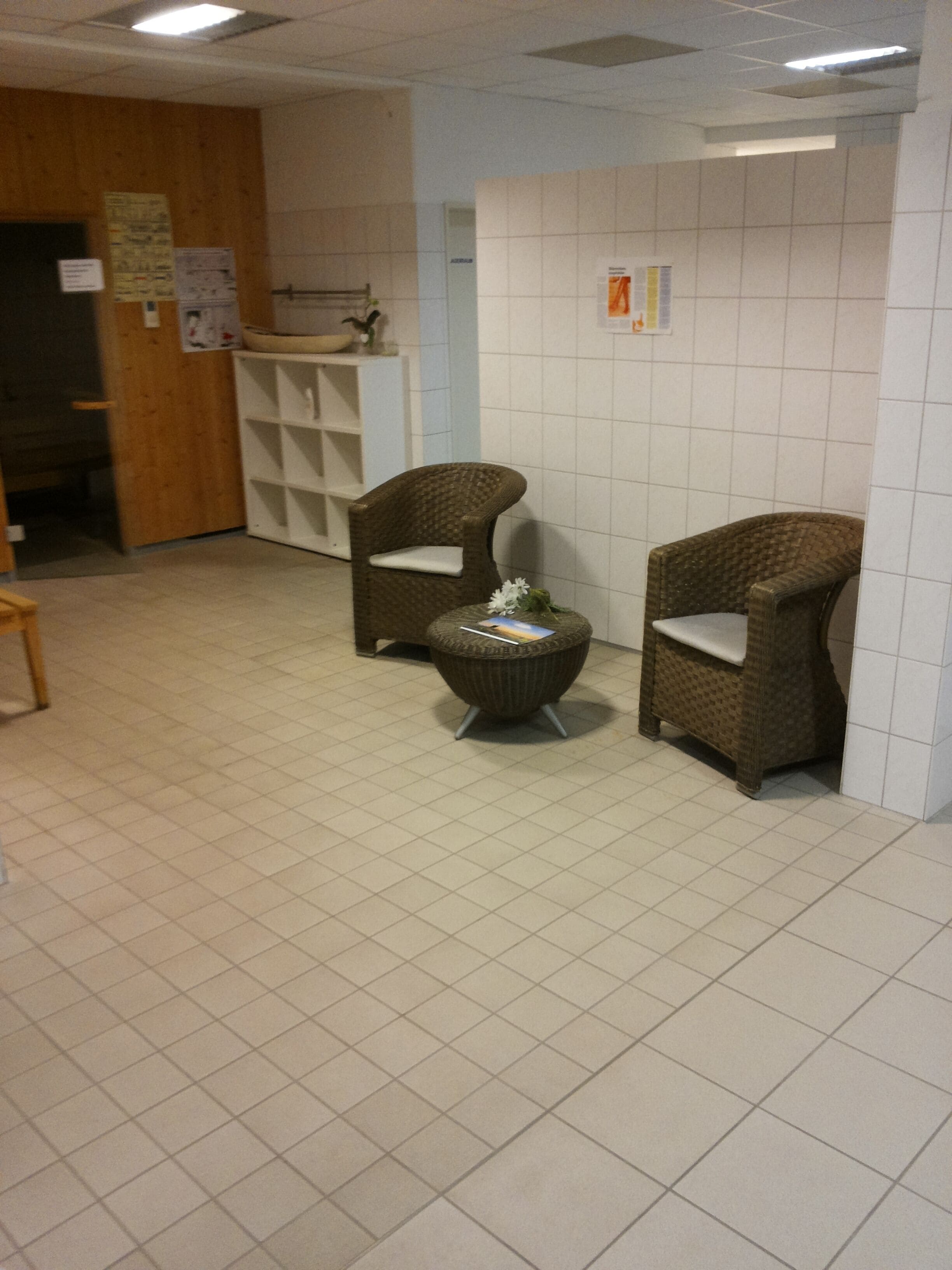 A room with two wicker chairs, a small round table, and a tiled floor.