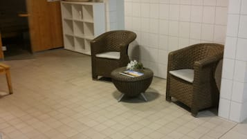 A room with two wicker chairs, a small round table, and a tiled floor.