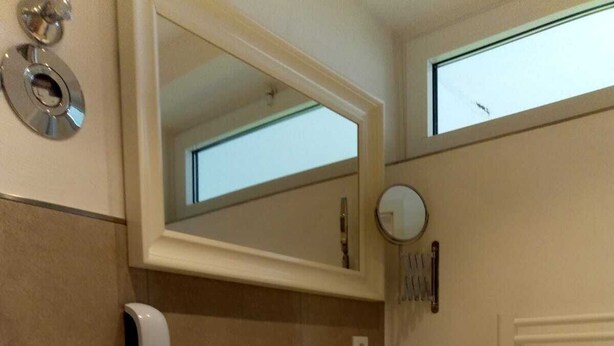 A bathroom with a white sink, a mirror above it, a hand dryer, and a towel rack. - Apartment Regina am schönen Möhnesee (Moehnesee)