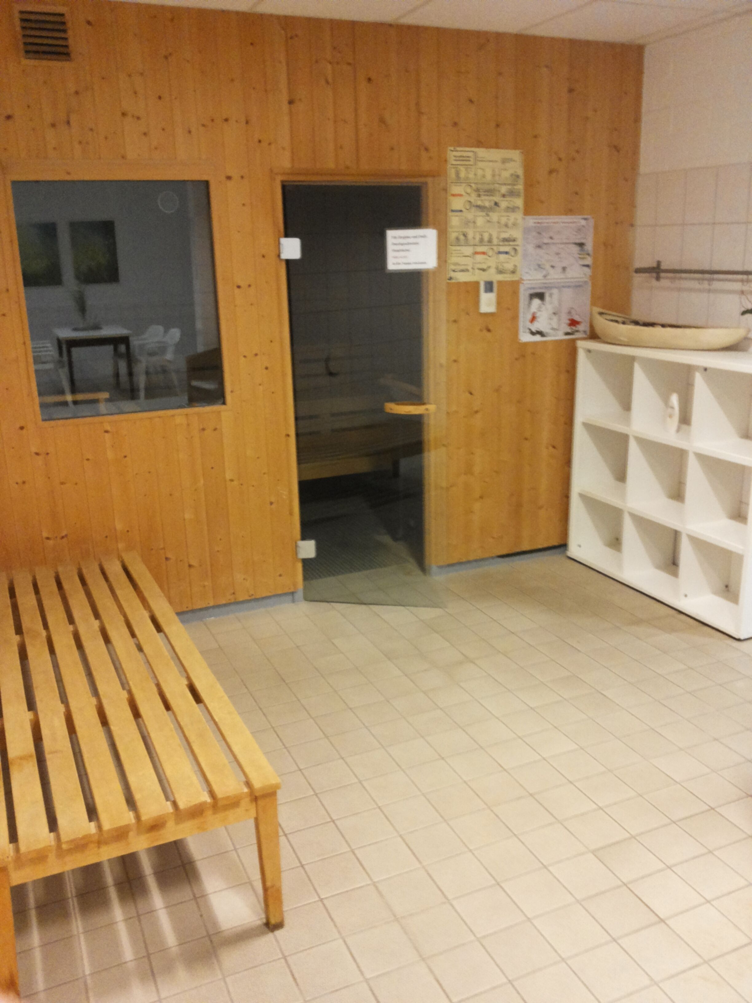 Een houten interieur met een bank, een deur en een wit wandrek.