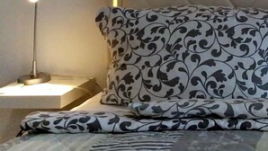A neatly made bed with patterned bedding, a bedside lamp, and a decorative headboard. - Apartment Regina am schönen Möhnesee (Moehnesee)
