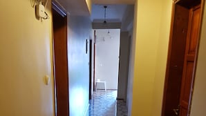 A hallway with patterned floor tiles, a white chair, and a ceiling fan. - Durak Hotel (Bodrum)