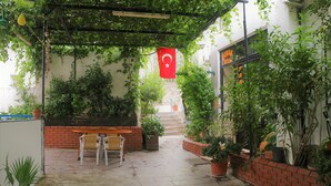 A covered patio area with a brick wall, potted plants, and a flag. - Durak Hotel (Bodrum)