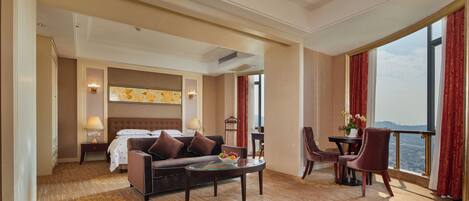 Habitación de hotel con cama, sofá, mesa de centro, una silla y vistas a la ciudad.