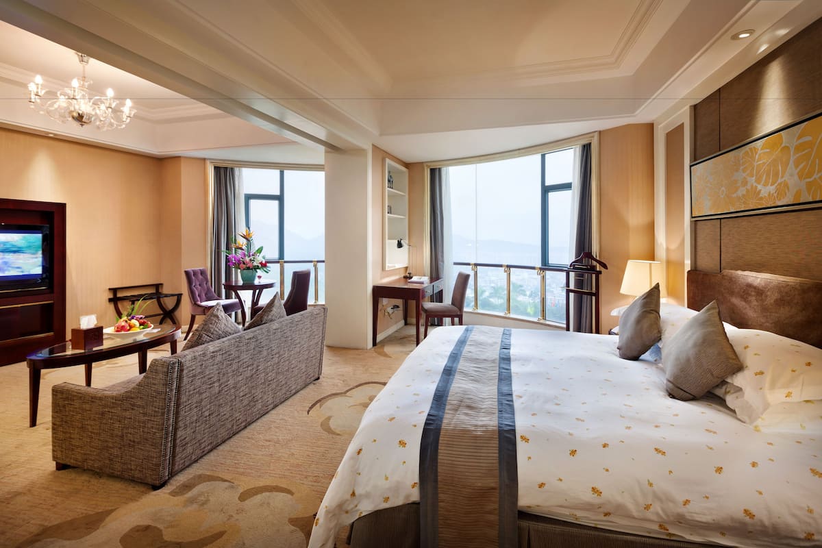 Ein Hotelzimmer mit einem großen Bett, einer Couch, einem Schreibtisch und einem Fernseher.