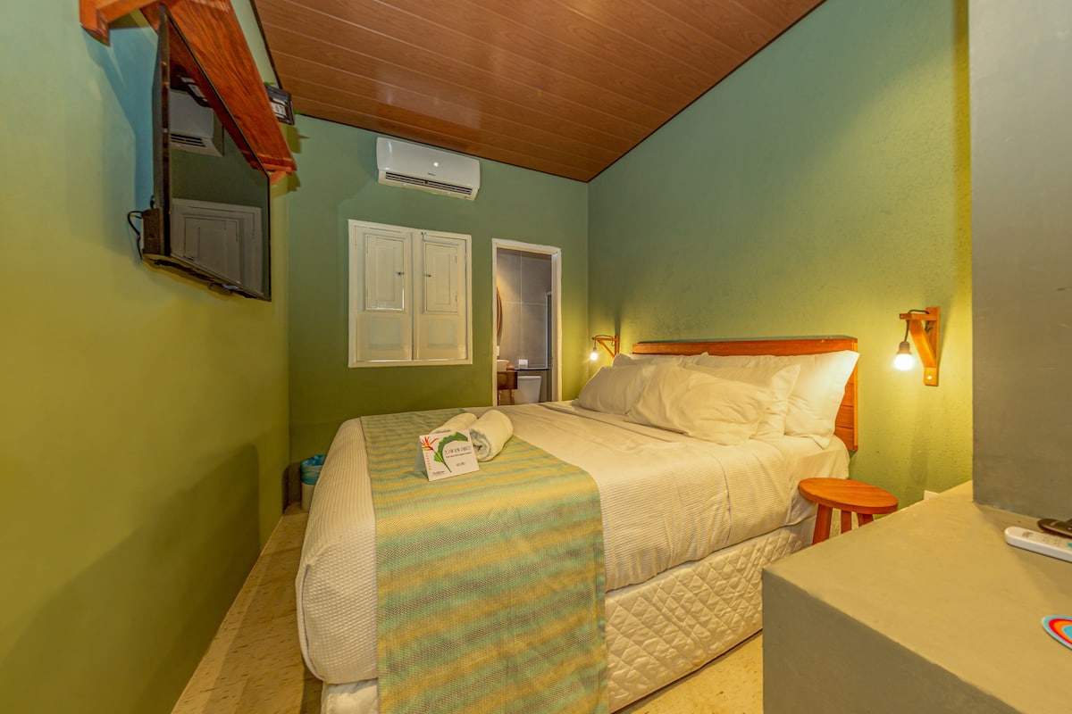 A bedroom with a bed, bedside table, and a mirror.
