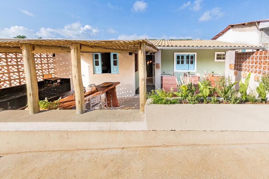 Propiedad residencial con zona de estar exterior cubierta, jardín con plantas y una casa con techo de tejas.