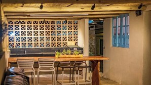 Una cocina con barra y taburetes de madera, un separador de celosía y una puerta azul.
