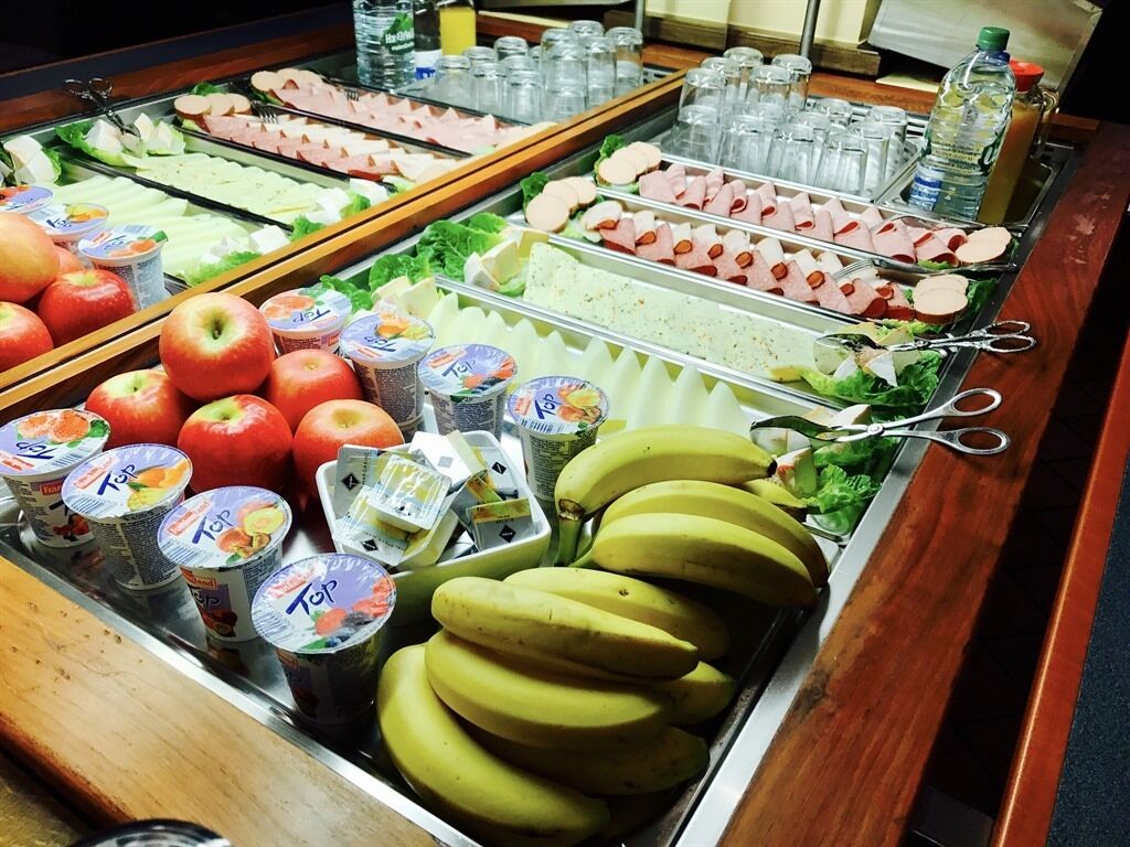 Ein Buffet mit verschiedenen Speisen, darunter Äpfel, Bananen und unterschiedliche Fleischsorten.