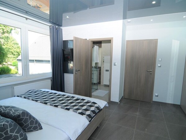 Un dormitorio moderno con una cama grande, un vestidor amplio y un baño visible a través de una puerta abierta.
