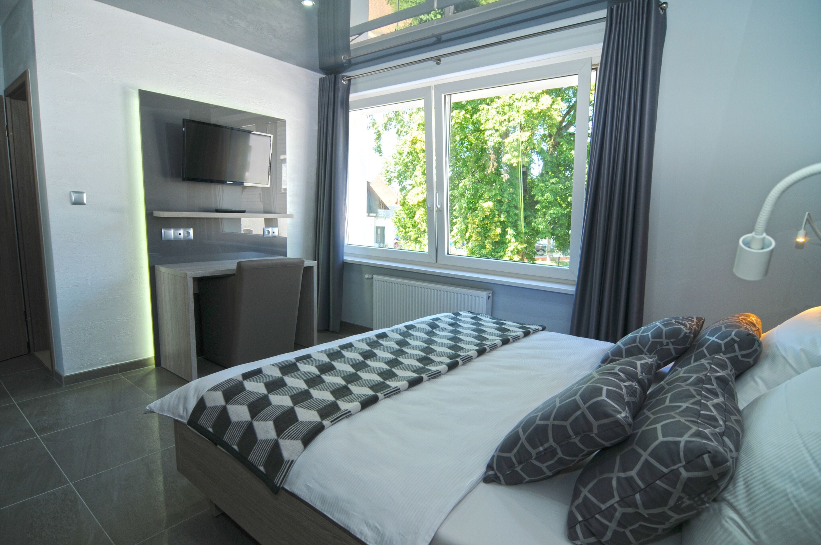 Un dormitorio moderno con una cama, un escritorio y un televisor.