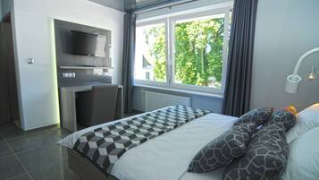 Un dormitorio moderno con una cama, un escritorio y un televisor.
