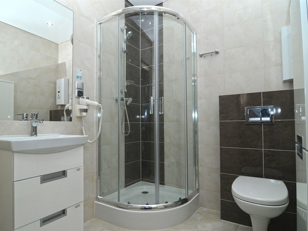 Un bagno moderno con doccia vetro, lavabo bianco e water.