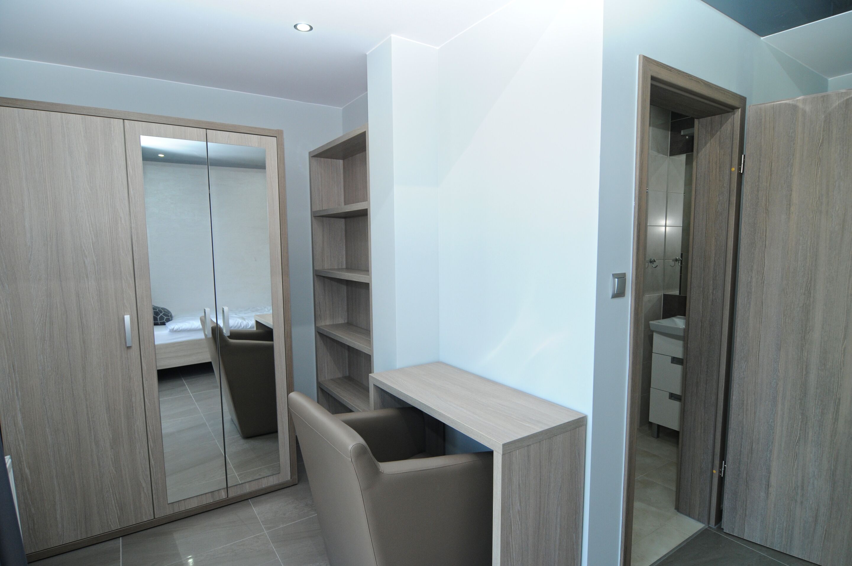A modern bedroom with a wardrobe, a bed, and a desk.
