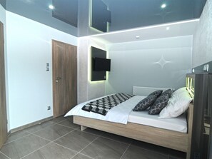 Une chambre à coucher moderne avec un lit, une télévision et une porte.