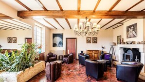Een ruime woonkamer met een open haard, leren banken en een grote plant.