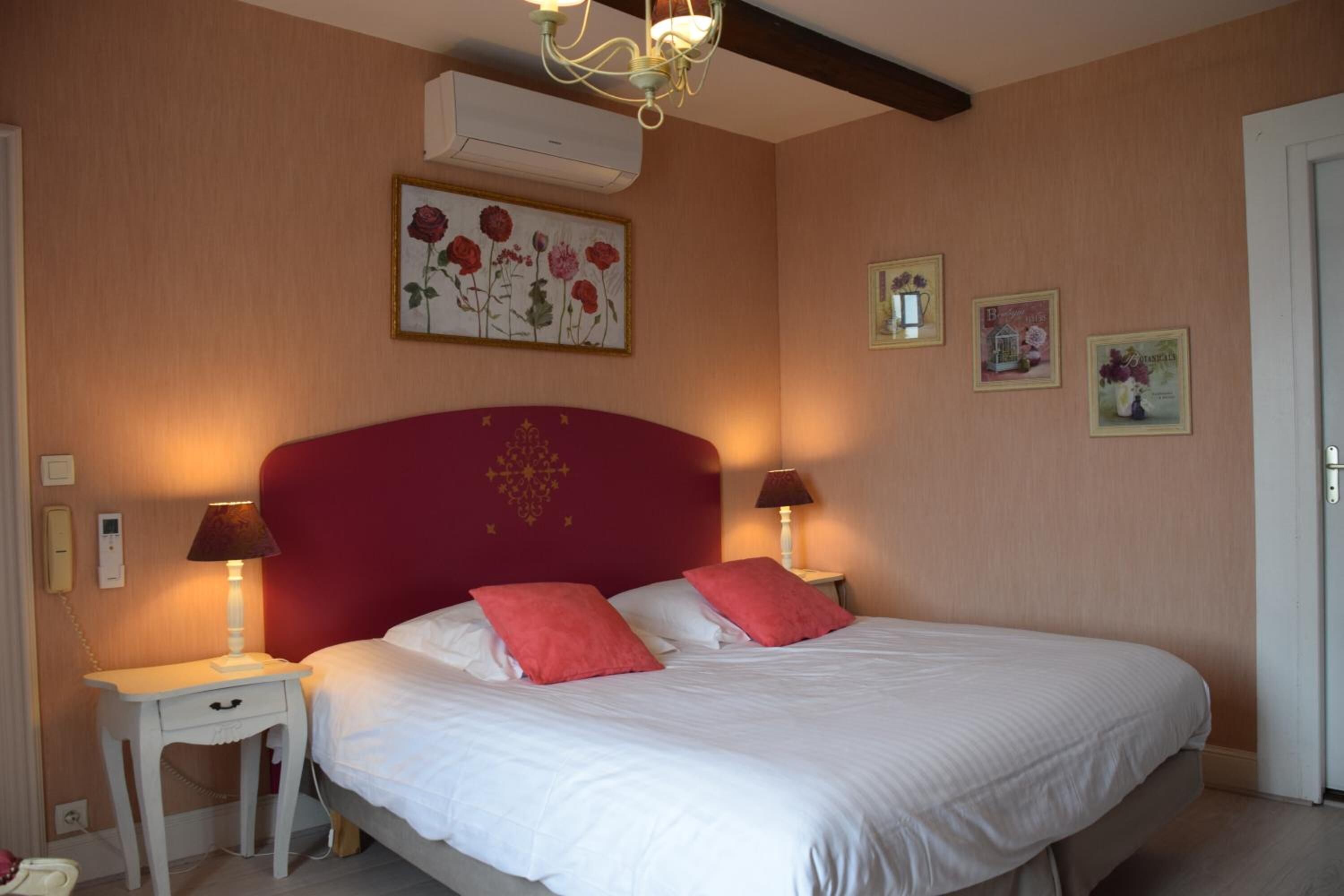 Un dormitorio con cabecera roja, ropa de cama blanca y dos lámparas de noche.