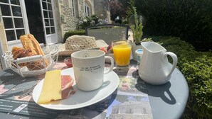 Een ontbijttafel met eten op een bord, een mok en een karaf sinaasappelsap.