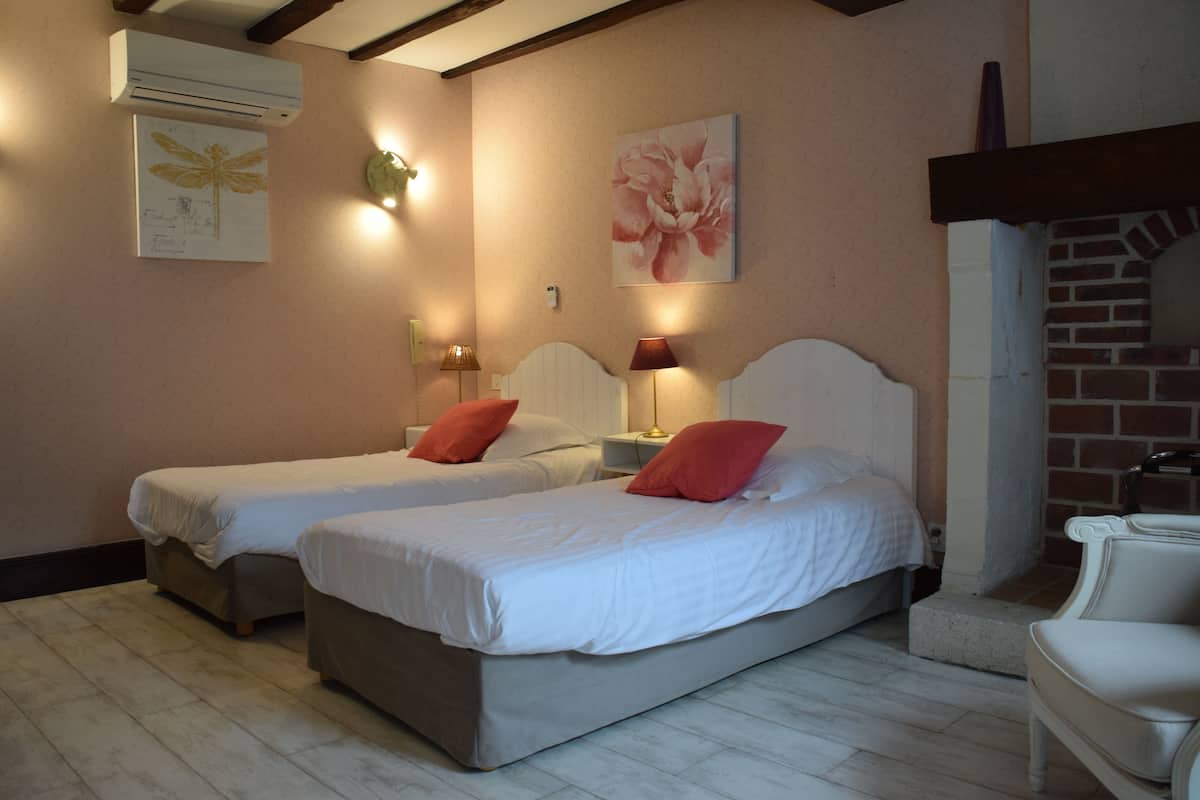 Una habitación de hotel con dos camas individuales, una chimenea de ladrillo y obras de arte colgadas en la pared.