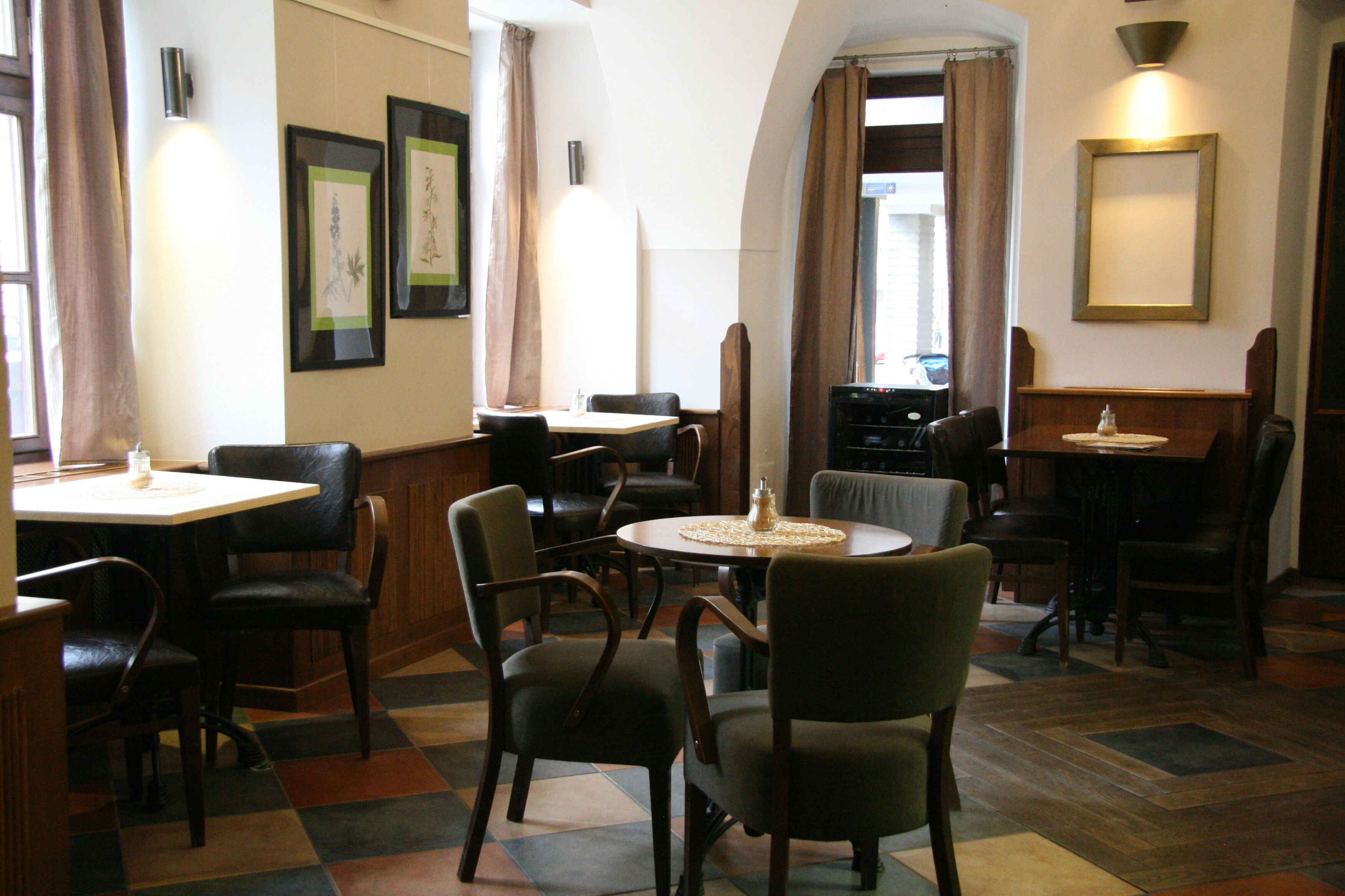 Un restaurante con varias mesas y sillas, obras de arte enmarcadas en las paredes y un suelo con estampado de espiga.