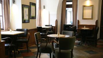 Un restaurante con varias mesas y sillas, obras de arte enmarcadas en las paredes y un suelo con estampado de espiga.