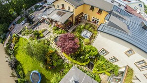 An aerial view of a residential area with a well-maintained garden, a trampoline, and a house with a sloped roof. - Hotel U Zvonu (Vrchlabi)