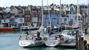 A marina with several boats docked, surrounded by residential buildings. - Lichfield House (Weymouth)