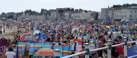 Una playa concurrida, gente, sombrillas y carpas de playa.