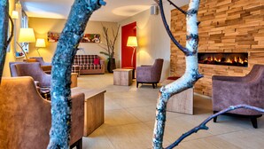 Un área de descanso moderna con sofás y sillones, una pared de madera con chimenea y una pared de acento roja.