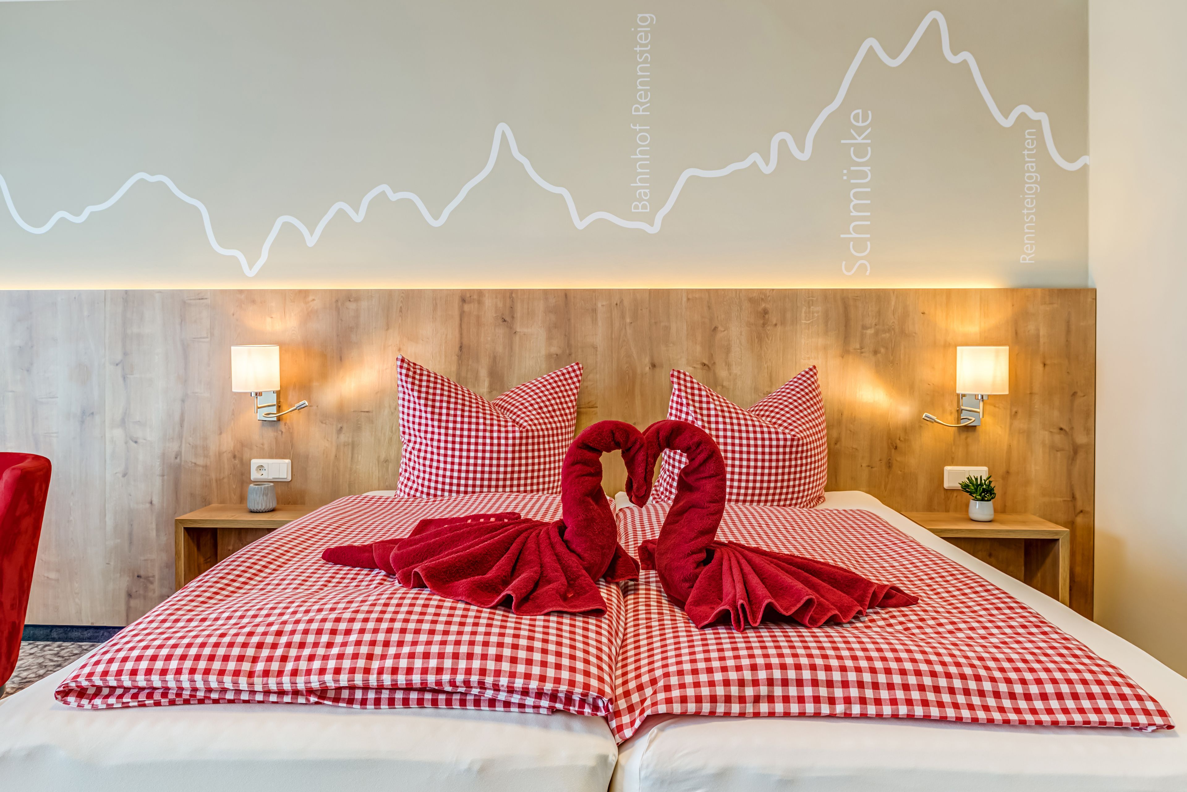 A hotel room with a wooden headboard, checkered bedding, two bedside lamps, and a wall-mounted light display.