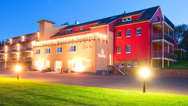 Un hotel de varios pisos con fachada roja, balcones y un letrero que dice "Traumblick".