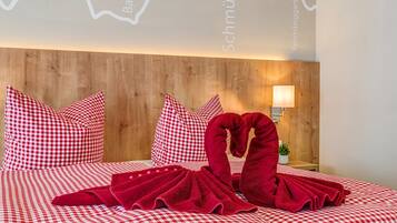 Ein Hotelzimmer mit Holz-Kopfteil, karierter Bettwäsche und einer roten Handtuchskulptur.