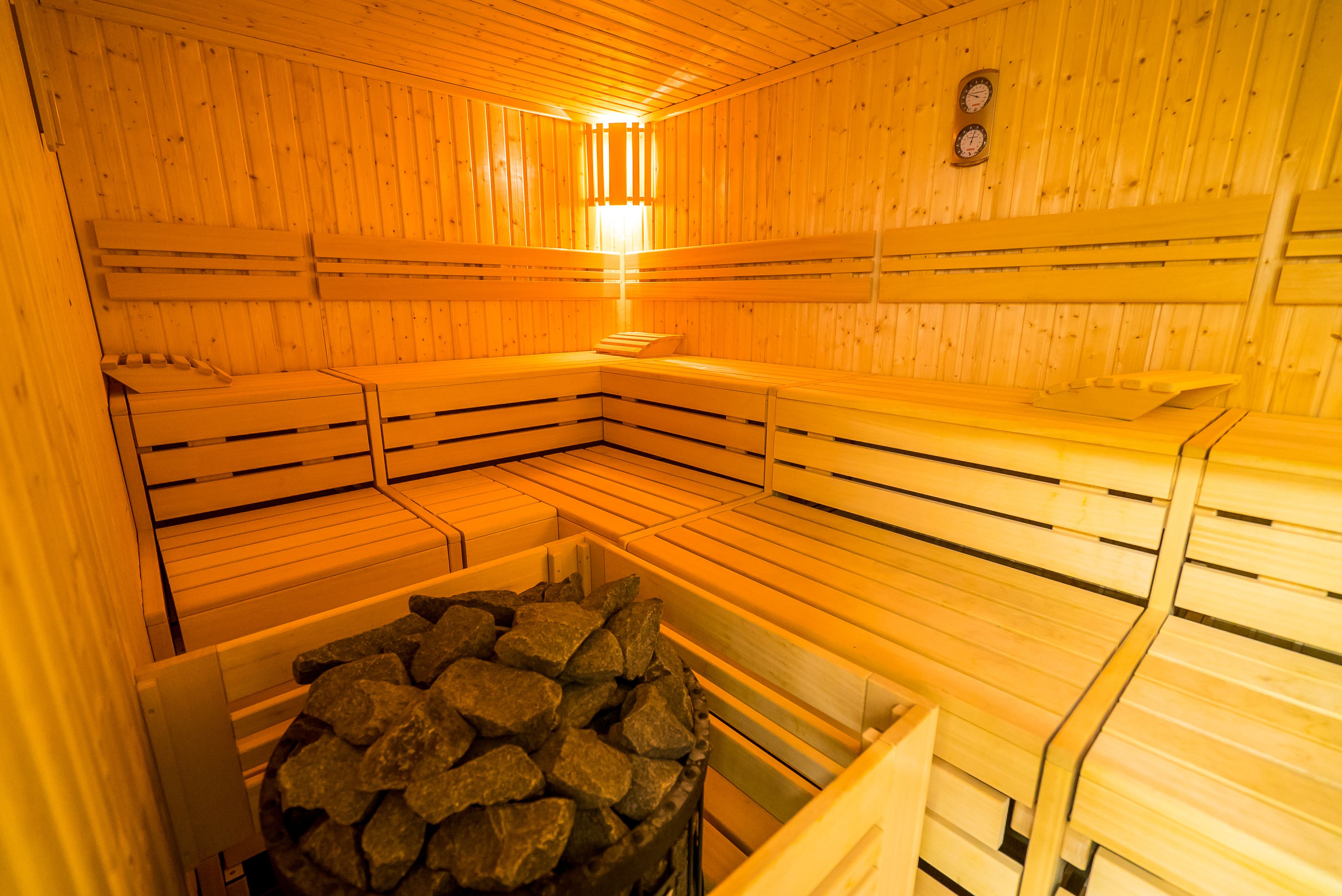 Eine Sauna mit Holzbänken und einem steinbelegten Behälter.