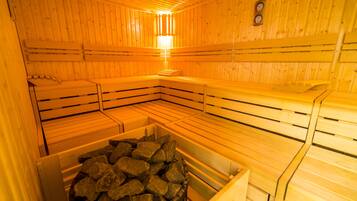 Eine Sauna mit Holzbänken und einem steinbelegten Behälter.