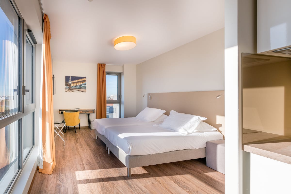 Une chambre d’hôtel moderne dotée d’un grand lit, d’un bureau et offrant une vue sur la ville.