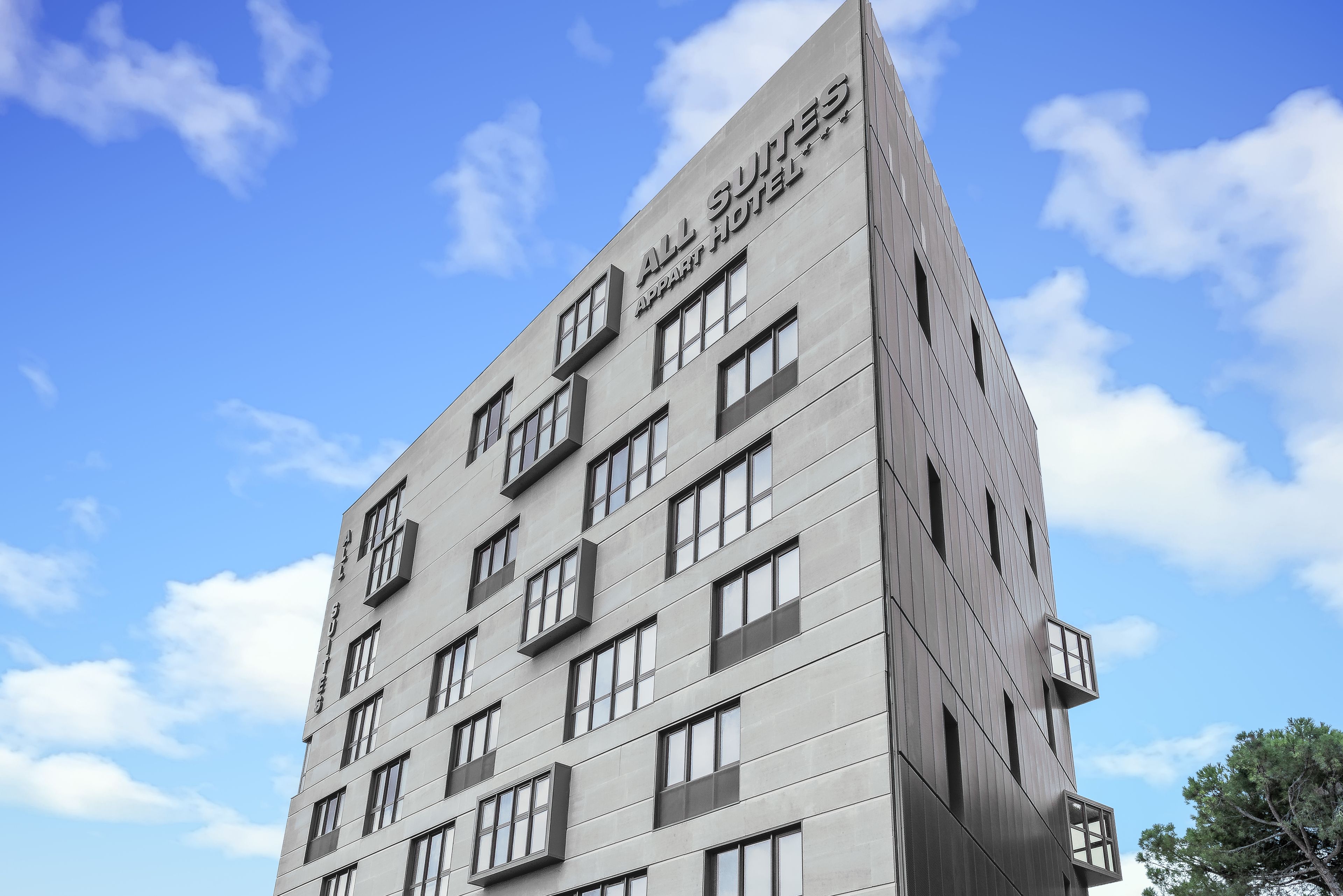 En moderne hotelbygning med flere etager og store vinduer.