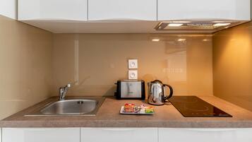 A modern kitchen with a stainless steel sink, a toaster, a kettle, and a black induction cooktop.