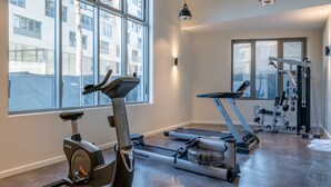 Ein Fitnessstudio mit Trainingsgeräten, großen Fenstern und einer roten Pendelleuchte.