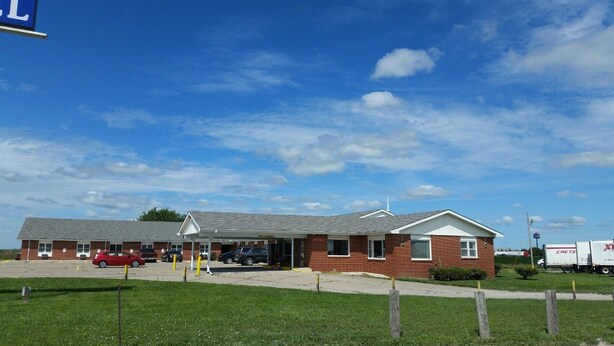 A single-story building with a brick facade, a covered parking area, and a truck parked outside.