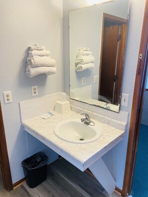 A bathroom with a white sink, a mirror, and a towel rack.