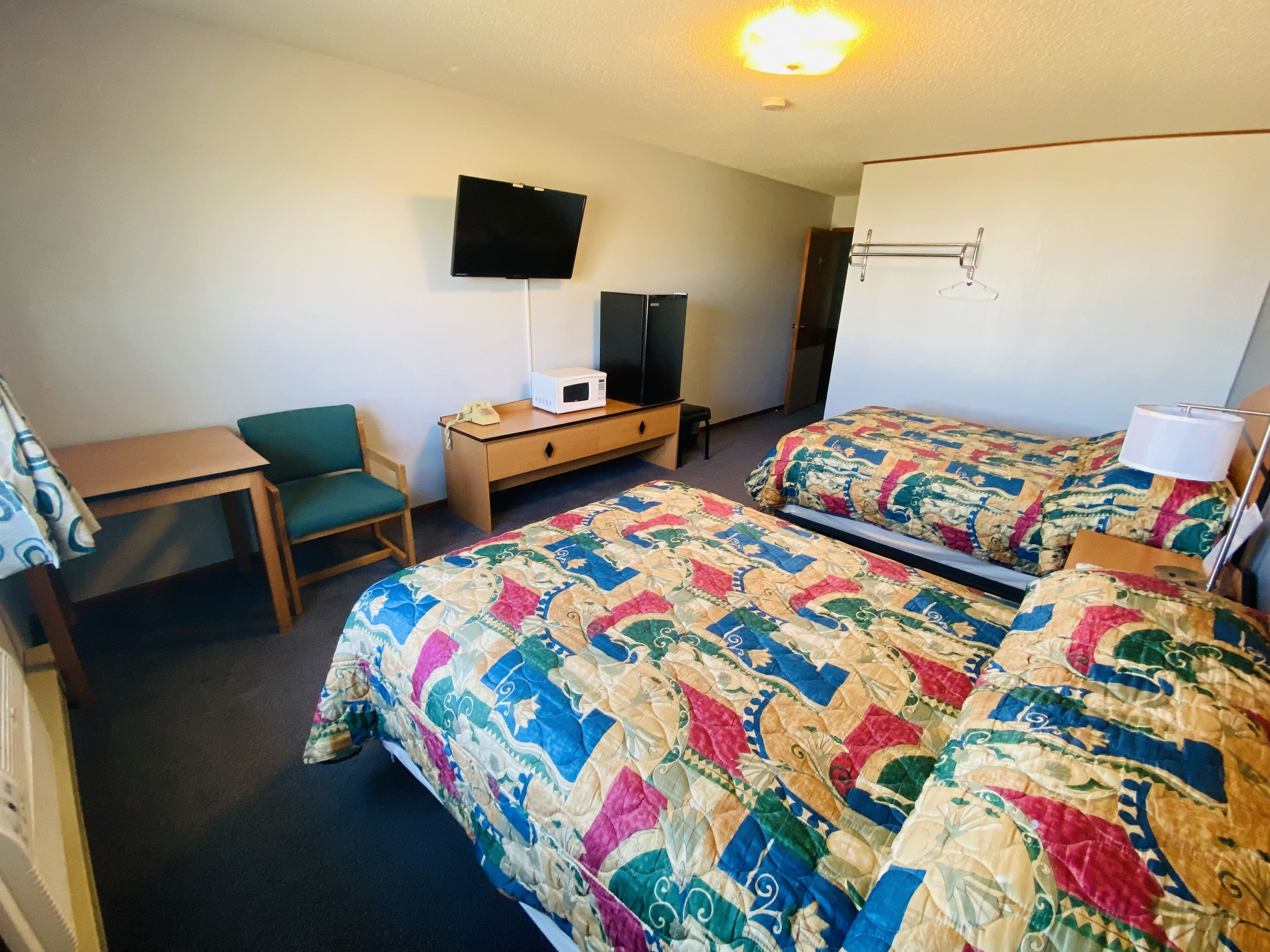 Hotelkamer met twee bedden, een bureau, een stoel, een televisie en een magnetron.