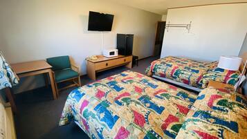 A hotel room with two beds, a desk, a chair, a television, and a microwave.