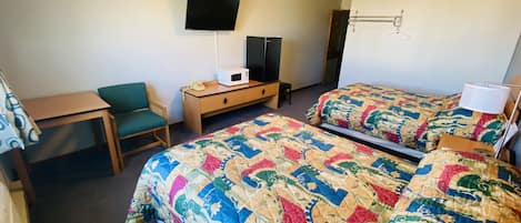 Hotelkamer met twee bedden, een bureau, een stoel, een televisie en een magnetron.