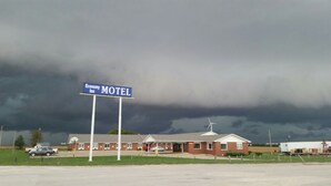 A motel with a sign indicating its name, a wind turbine, and a stormy sky in the background.