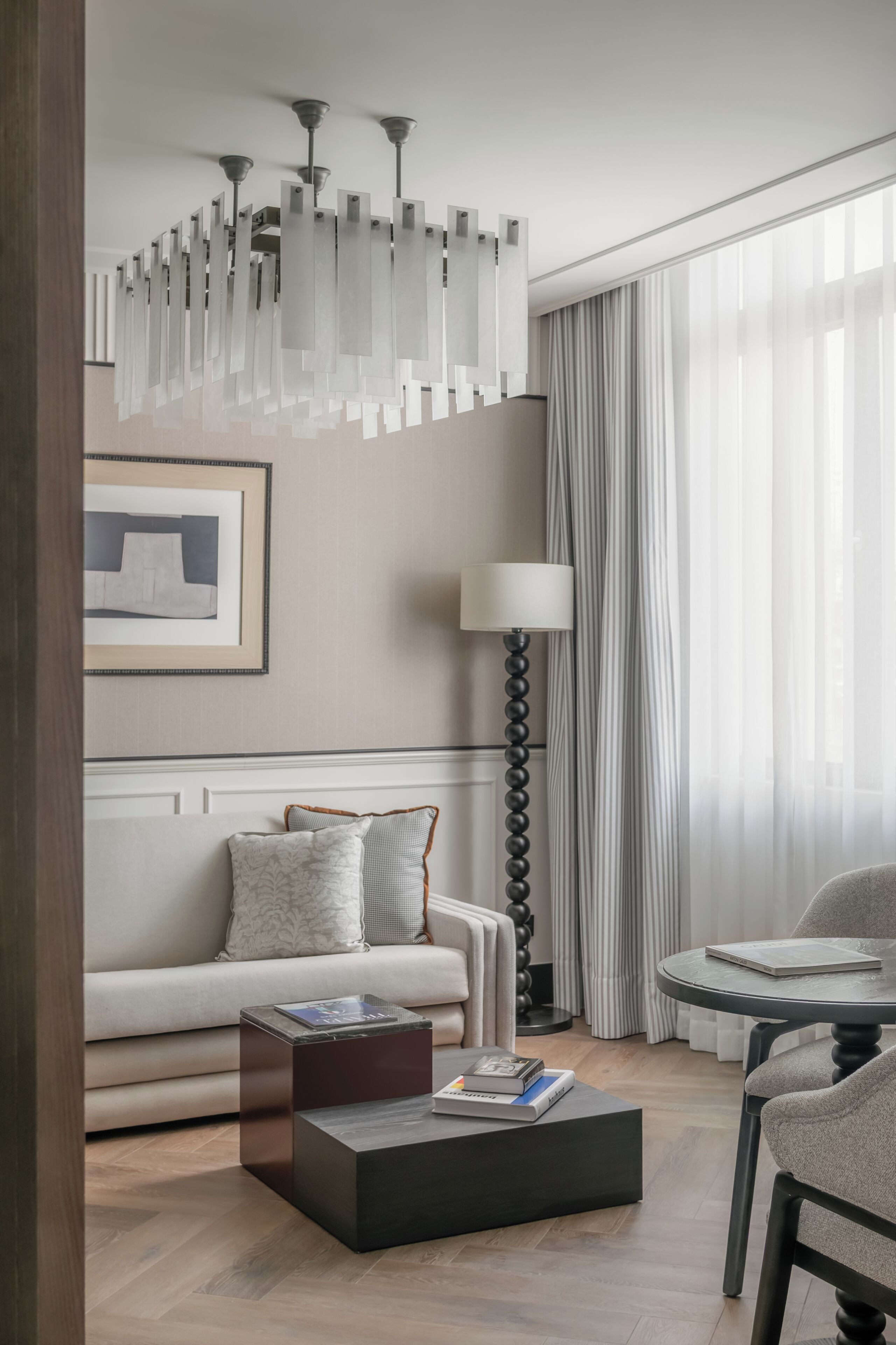 A modern hotel room with a sofa, a coffee table, a lamp, and a chair.