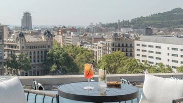 Una terraza en la azotea con una mesa redonda, dos sillas y vistas a un paisaje urbano.
