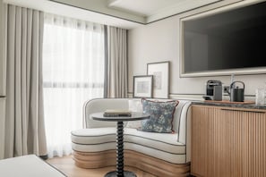 A modern living room with a curved sofa, a small round table, a flat-screen TV, and a coffee machine. - BLESS Barcelona - New Opening 2026  (Barcelona)