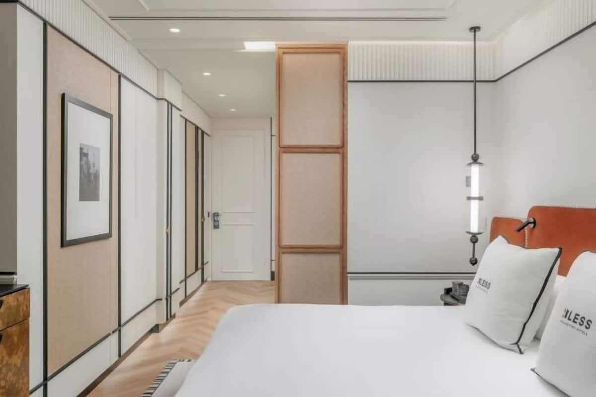 Ein modernes Hotelzimmer mit einem Bett, einem Kleiderschrank, einer Tür und einer Pendelleuchte.