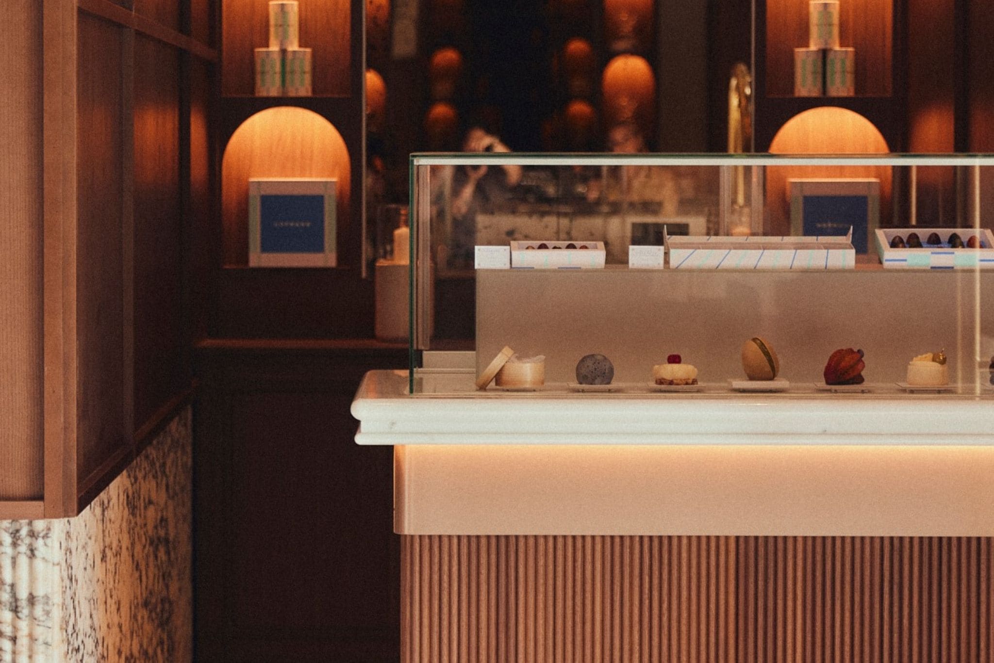 A dessert display case with various sweets and a wooden counter with a label.