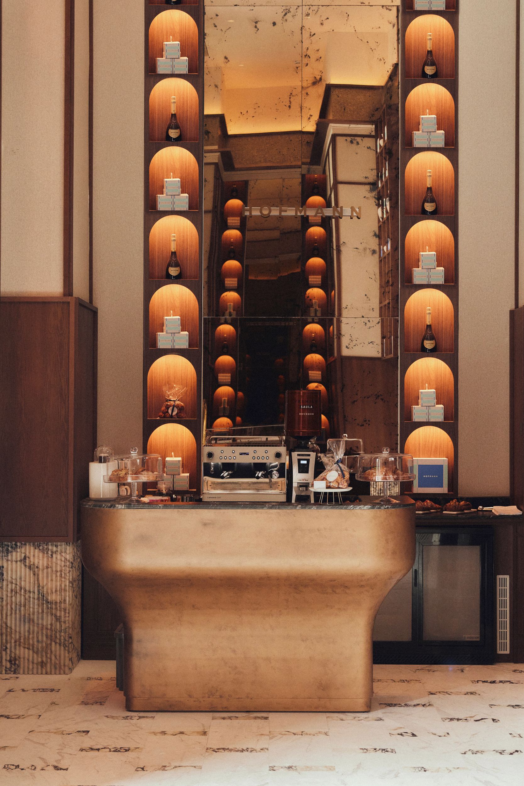 A bar area with a long counter, multiple bottles, and a coffee machine.
